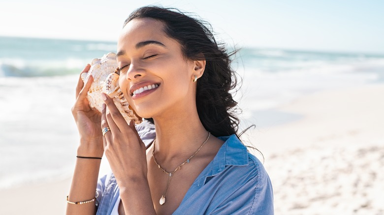 Woman listening to a seashell at the beach