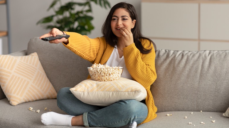 Woman eating popcorn on couch 