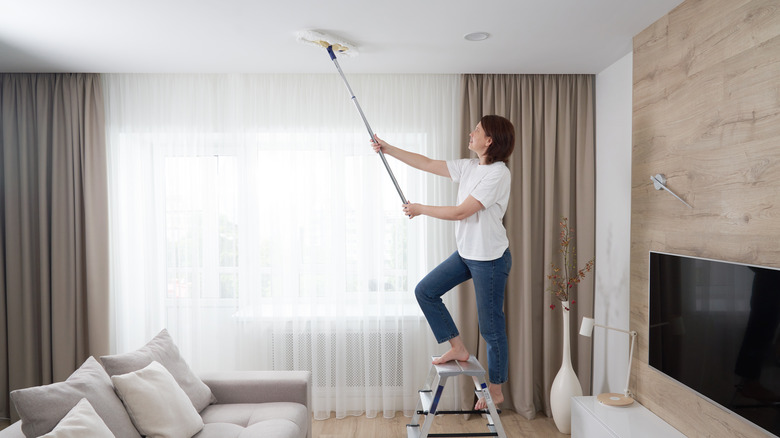 woman dusting ceiling