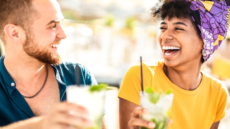 Laughing couple drinking cocktails
