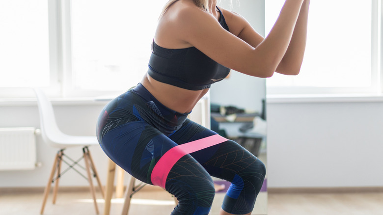 female squatting wearing a resistance band on her upper thighs