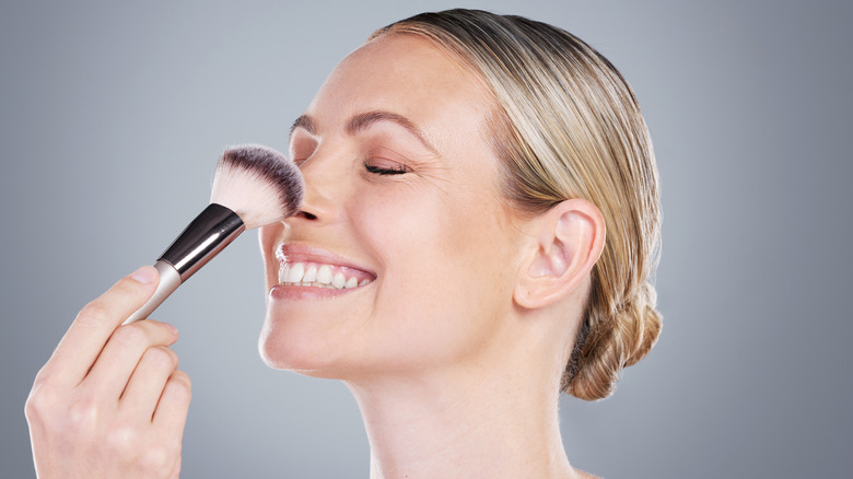 Woman looking in mirror with fluffly brush