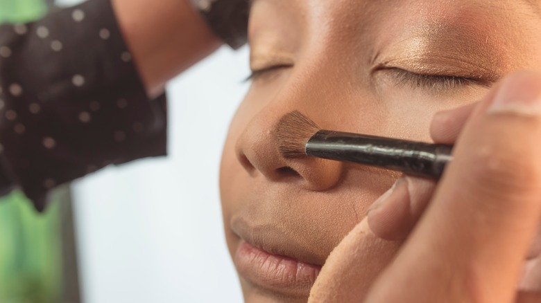 Woman blending makeup on nose