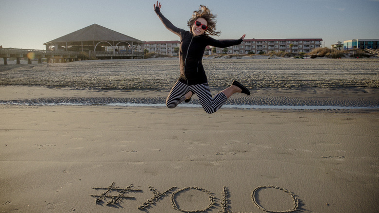 Woman jumping YOLO on sand