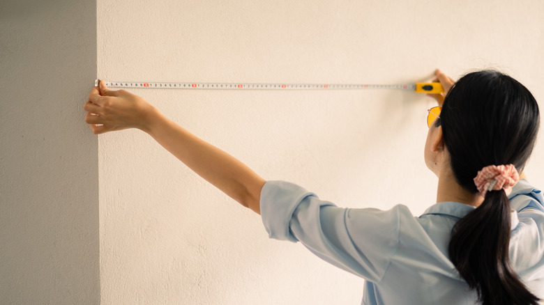 person measuring a wall