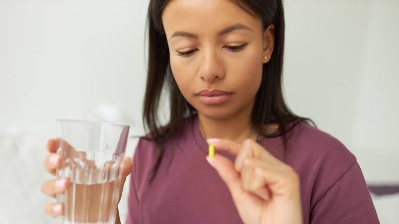 Woman looking at a capsule she is about to drink