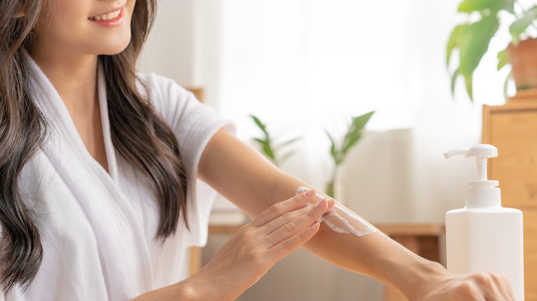 Woman applies moisturizer to arm