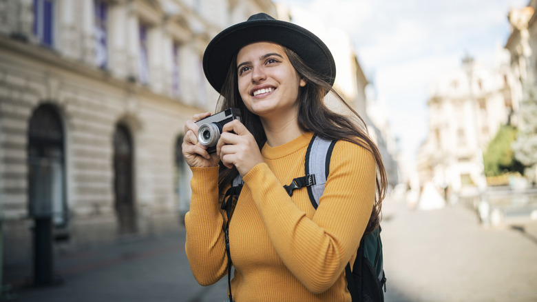 Solo female traveler wearing a hat and a bright-yellow top