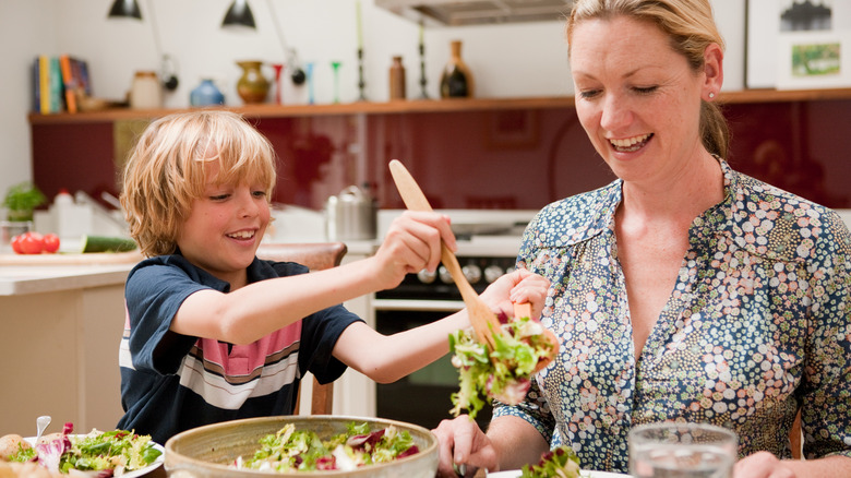 woman and boy sitting at table eating salad