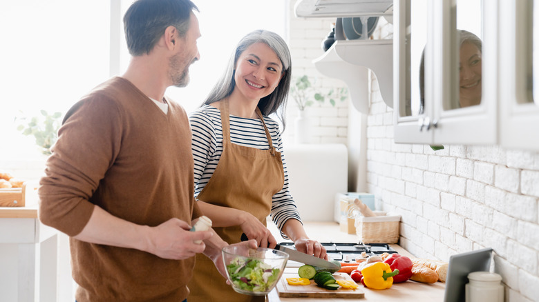 man woman cooking at stove vegetables