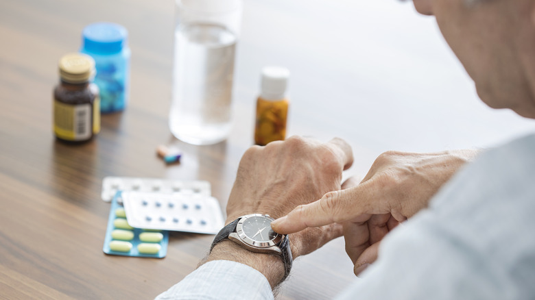 older gentleman looking at watch for pill schedule