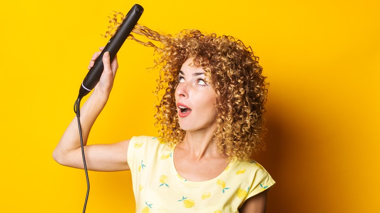 Woman straightening curly hair