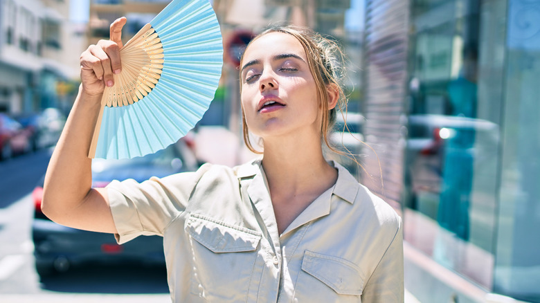 A woman fanning herself on a hot day