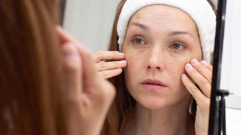 Woman looking at her wrinkles in mirror