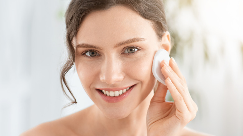 woman putting on skincare with a cotton pad