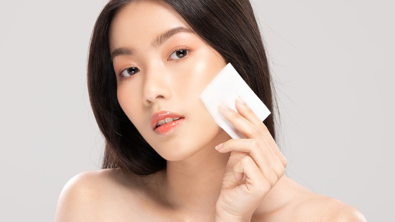 woman using toner with a cotton pad on the face