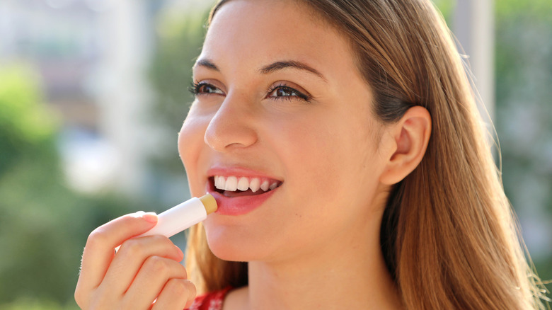 A woman applying lip balm 