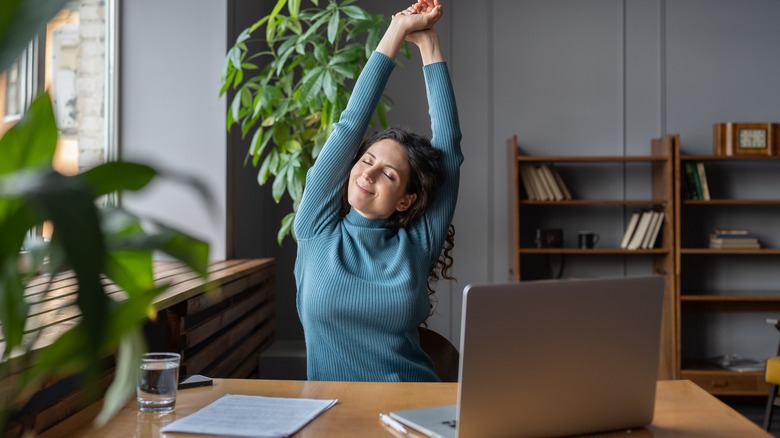 woman working on computer happy and stretching