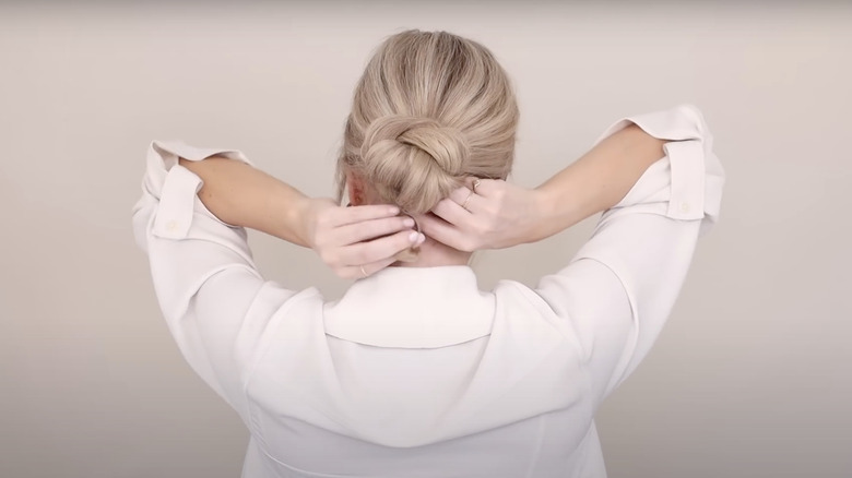 woman styling hair in bun