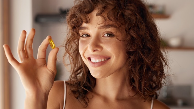 Woman holding vitamin and smiling