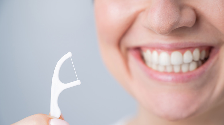 Floss pick held by smiling woman