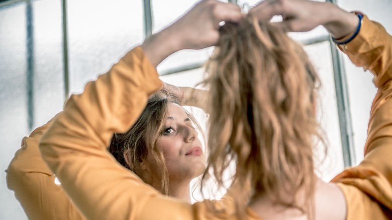 Woman styling ponytail in the mirror