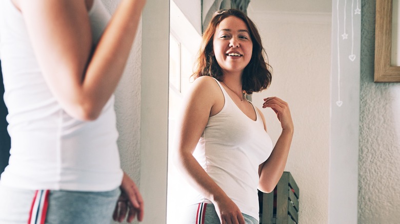 Woman looking at full-length mirror