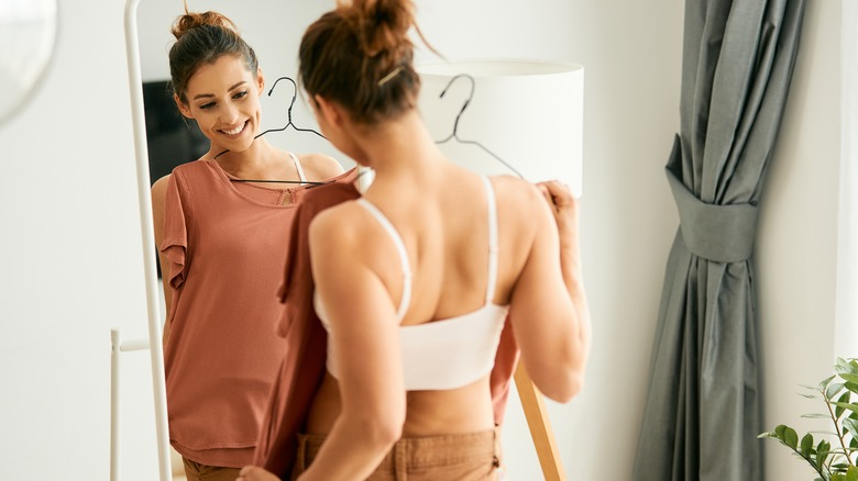 Woman looking at mirror while getting dressed