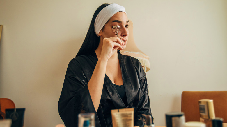 Woman doing her makeup routine with eyelash curler.