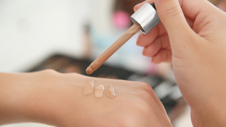 Woman applying concealer on hand 