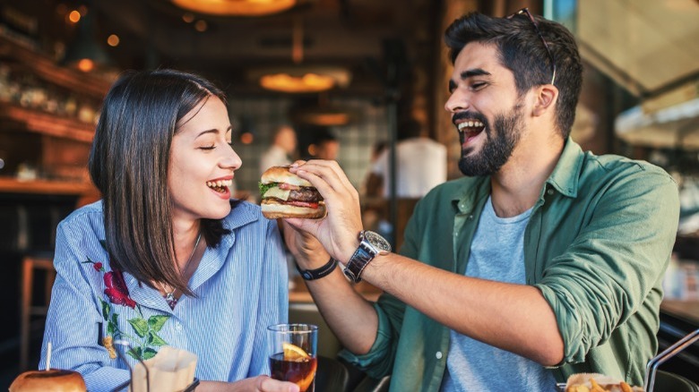 Man handing hamburger to woman