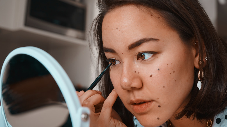 A woman putting on eyeliner