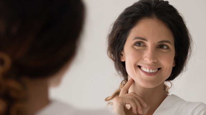 woman checking reflection in mirror