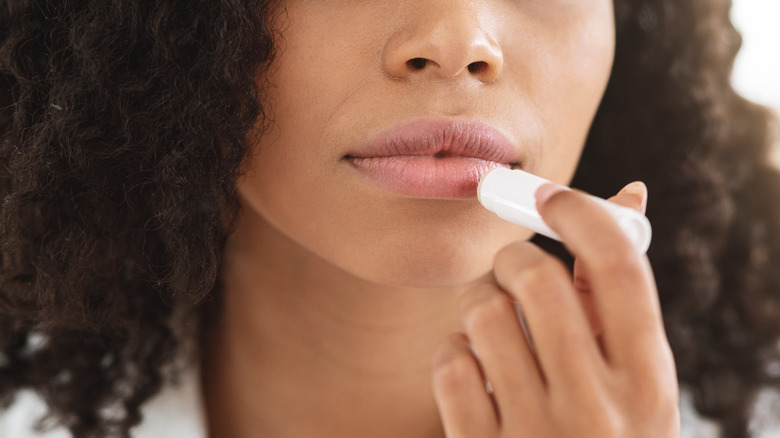 Woman applying lip balm to mouth