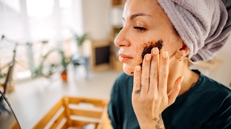 Woman exfoliating face with coffee scrub