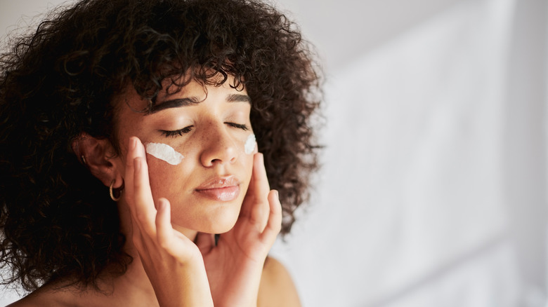 Woman applying face moisturizer