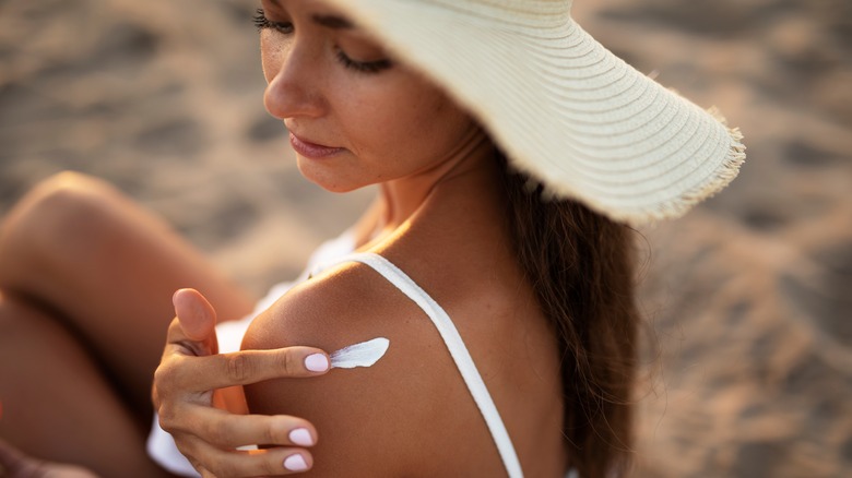 Woman applying sunscreen to shoulders on beach