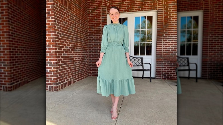 Woman poses wearing sage green dress 