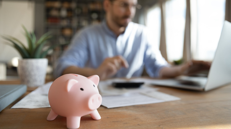 Man calculating finances with piggy bank