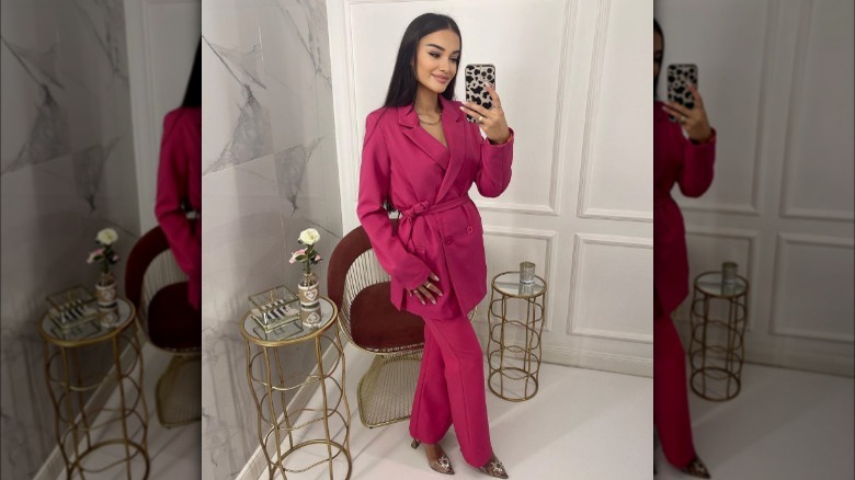 Woman in a red satin pantsuit taking a mirror selfie