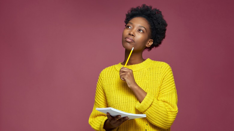 Woman thinking with pencil and notebook