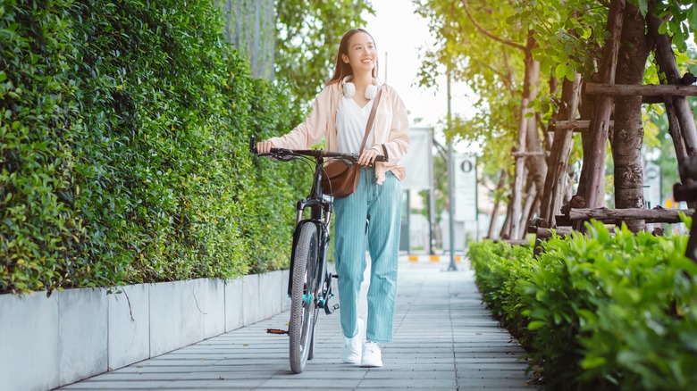 Woman walking bike in park