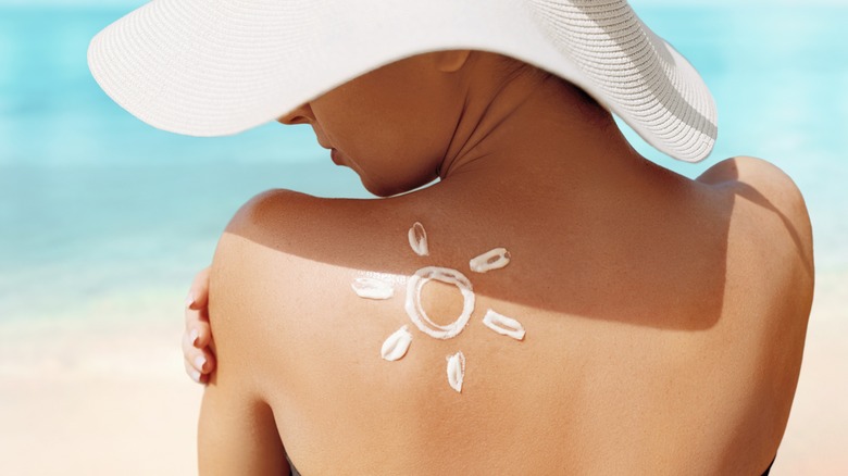 woman applying sunscreen to back