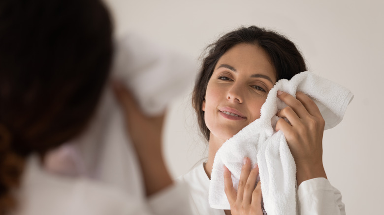 Woman patting face dry after cleansing