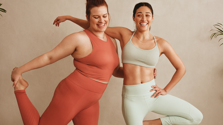 two women standing next to each other smiling in workout clothes