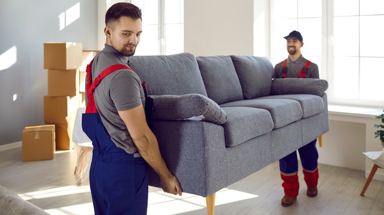 moving company carrying blue couch