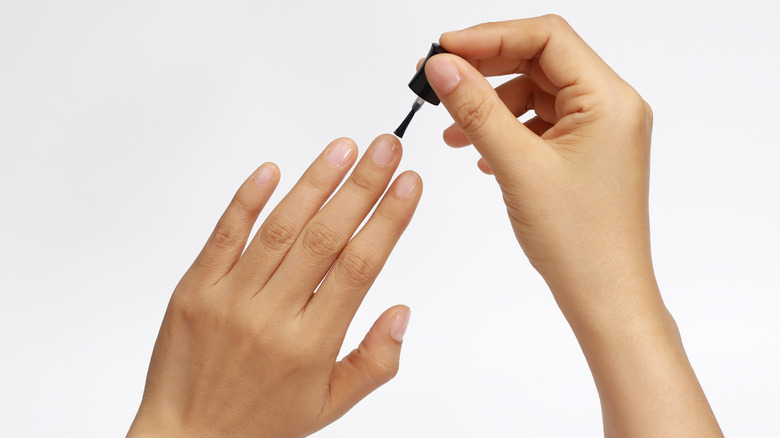 person applying clear nail polish