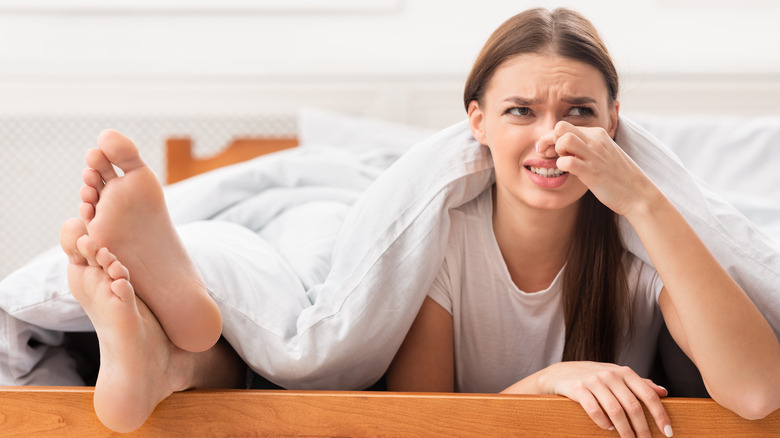 woman in bed holding nose