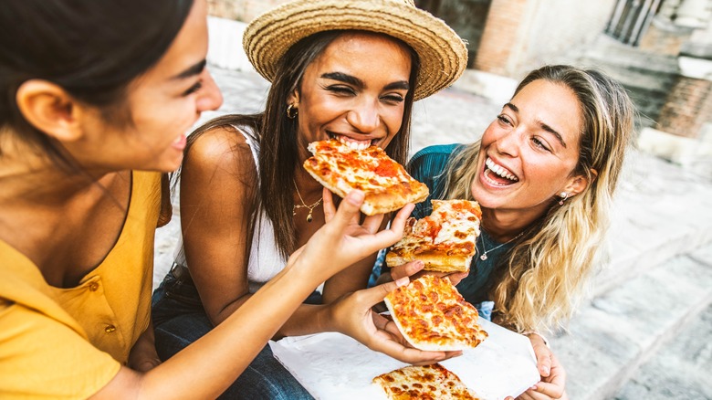 Friends eating pizza outside 