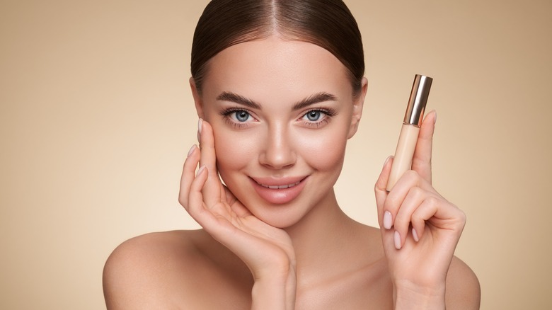 Woman holding concealer tube